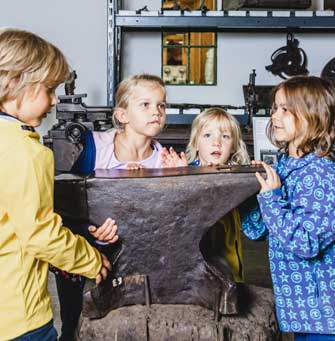 Kinder versuchen einen Amboss zu heben
